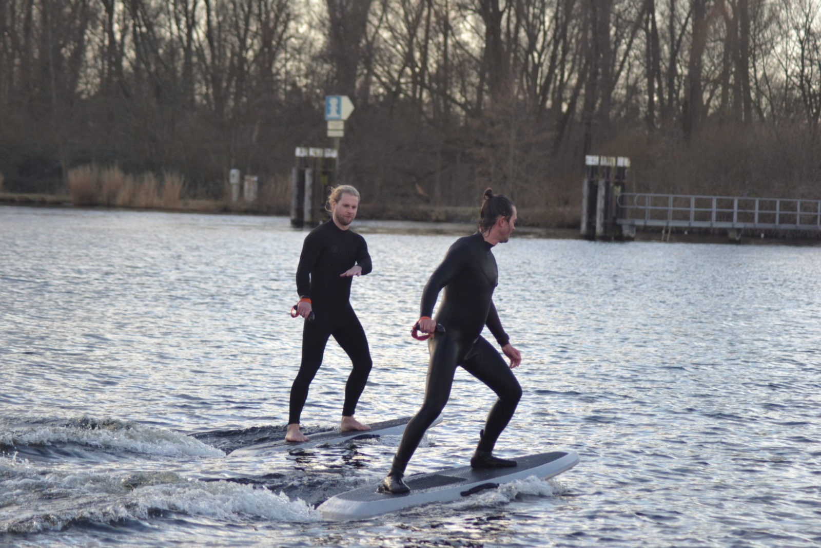 Twee personen aan het eFoilen in het water, waarvan 1 leerling en 1 instructeur.