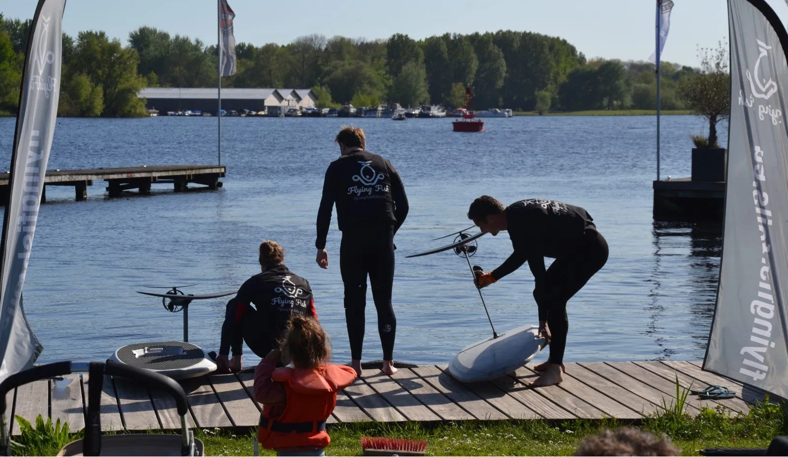 Drie Flying Fish instructeurs die op een steiger bezig zijn met twee eFoils klaarmaken