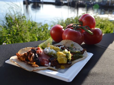 Lekkere maaltijd met vlees, groente en saus op een bord met tros tomaten ernaast