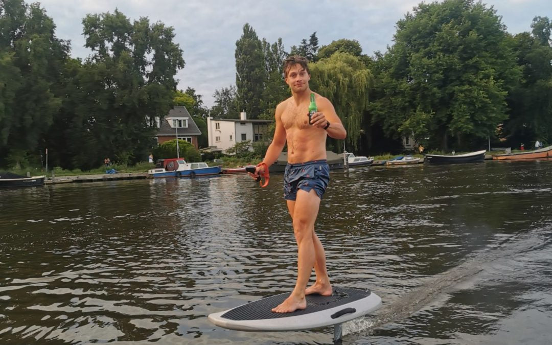 Man op een eFoil in het water met een biertje in zijn hand