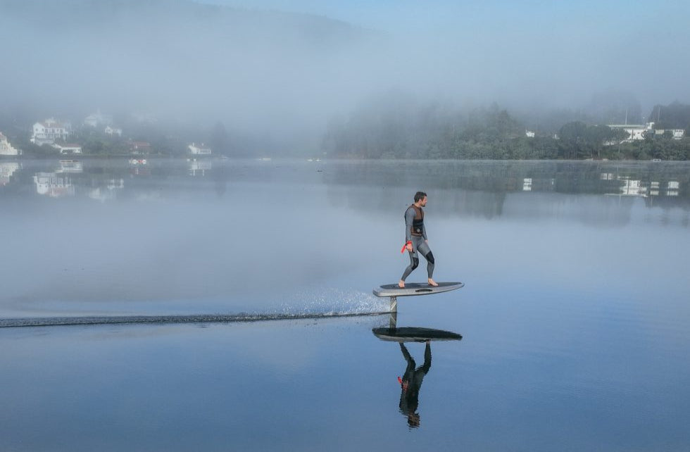 Man op het water op een Efoil met mist in de achtetgrond