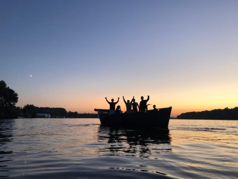 Groep mensen aan het varen op het water tijdens zonsondergang