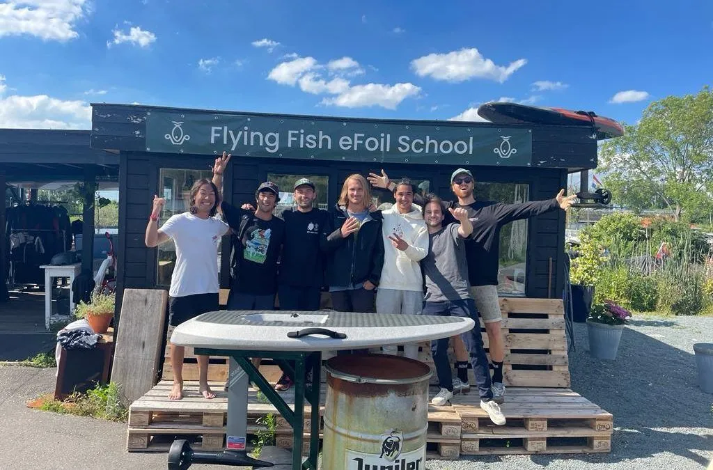 Groepsfoto voor het "Flying Fish eFoil school" bord