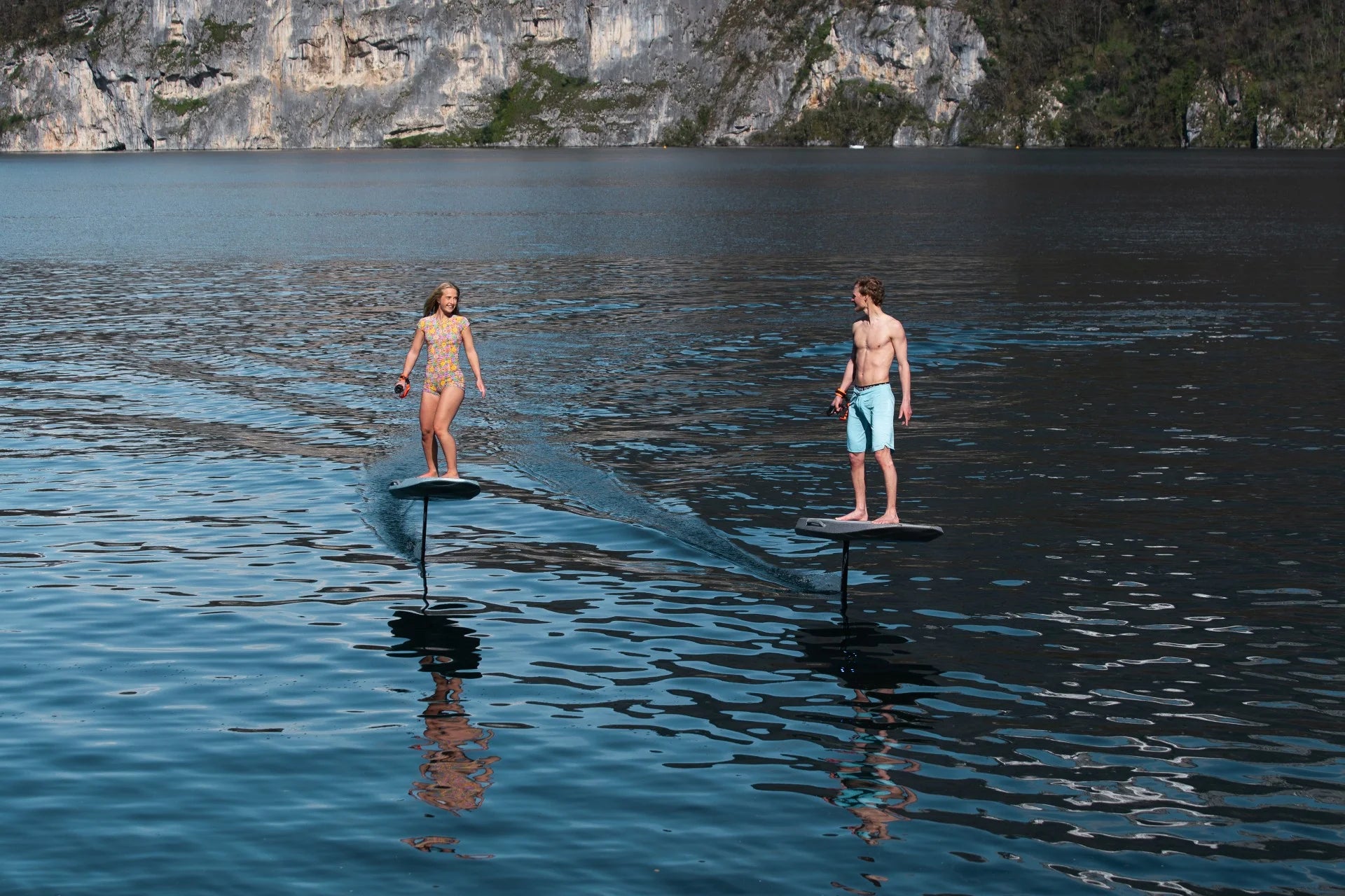 Man en vrouw aan het eFoilen op het water in bergachtig gebied.