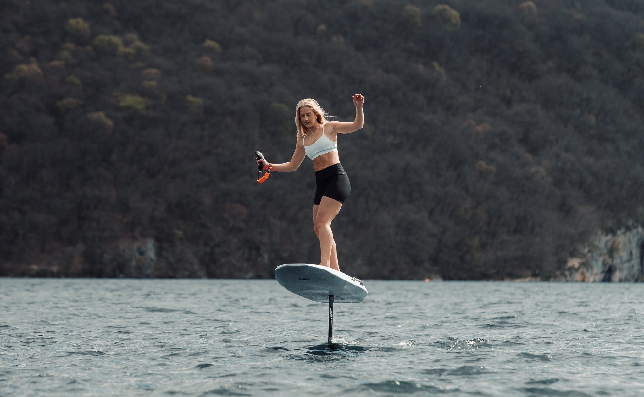 Vrouw aan het eFoilen op het water met een berg in de achtergrond